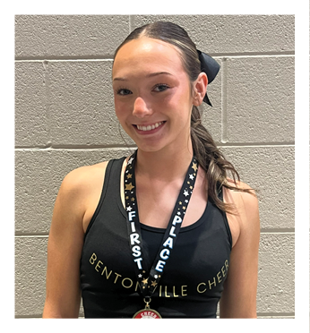A woman wearing a black tank top with a gold medal around her neck. Description generated by AI