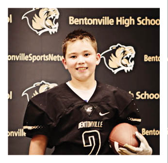 A young boy wearing a football jersey with the number 2 on it. Description generated by AI