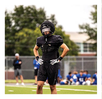 A football player wearing a black helmet and uniform. Description generated by AI