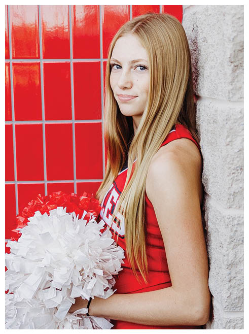 A cheerleader with long blonde hair holding a pom pom. Description generated by AI