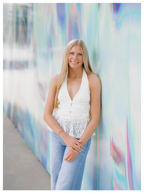 A woman is posing for a picture in front of a colorful wall. Description generated by AI