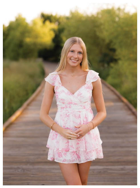 A woman wearing a pink dress and gold necklace. Description generated by AI