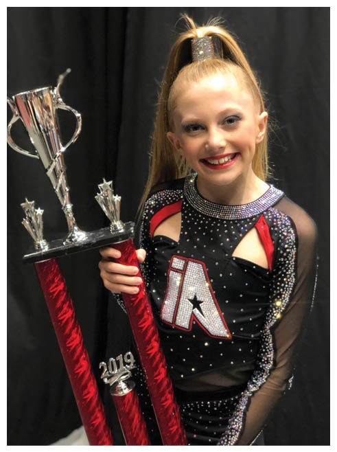 A girl holding a trophy with the letters IA on it. Description generated by AI