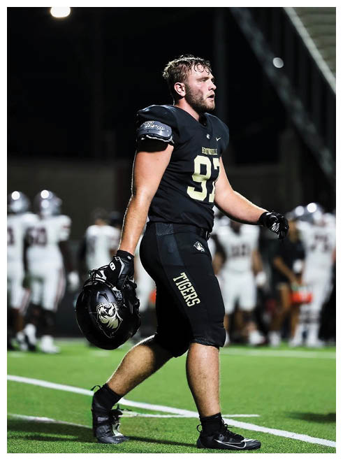 A football player wearing a black jersey with the number 90 on it. Description generated by AI
