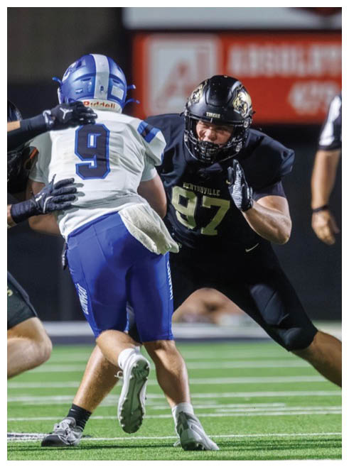 A football player in a black jersey is running with the ball. Description generated by AI