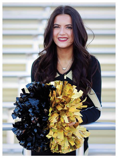 A cheerleader holding a black and yellow pom pom. Description generated by AI