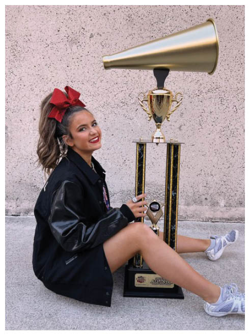 A girl is sitting on the ground next to a trophy. Description generated by AI