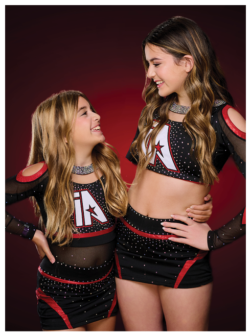 Two young girls wearing matching outfits. Description generated by AI