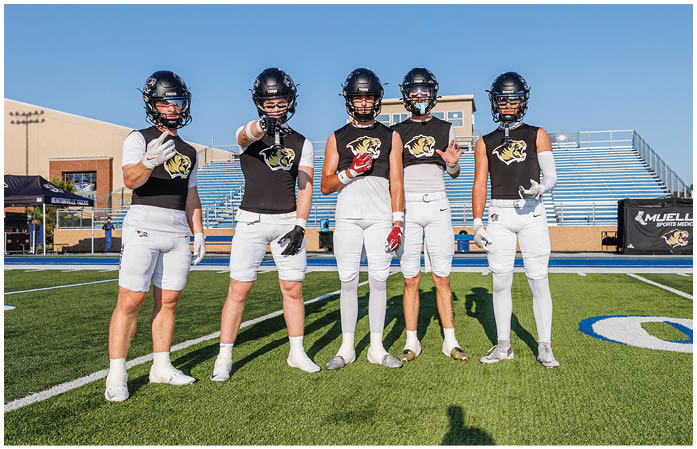 A group of football players standing on a field. Description generated by AI