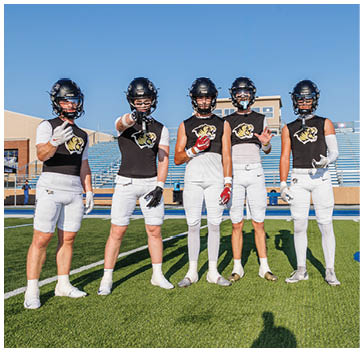 A group of football players standing on a field. Description generated by AI