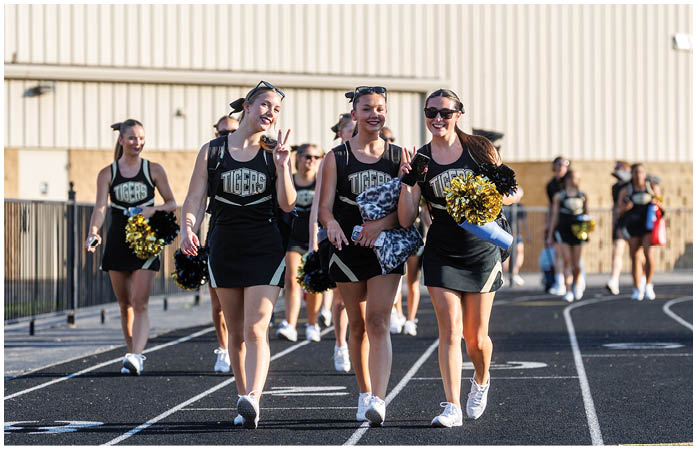 A group of cheerleaders walking on a track. Description generated by AI