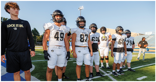 A group of football players standing on a field. Description generated by AI