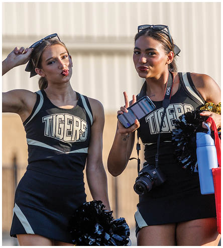 Two cheerleaders wearing black and gold uniforms. Description generated by AI