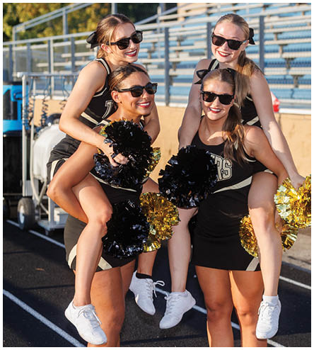 A group of cheerleaders posing for a picture. Description generated by AI