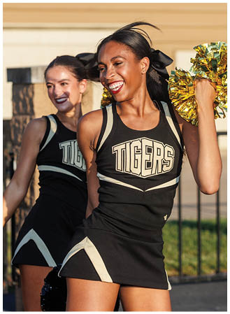 Two cheerleaders in black and white uniforms with yellow pom poms. Description generated by AI