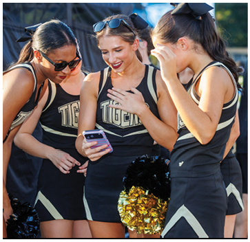 Three cheerleaders wearing black and gold uniforms. Description generated by AI