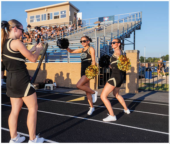 Two cheerleaders in uniforms are on a track. Description generated by AI