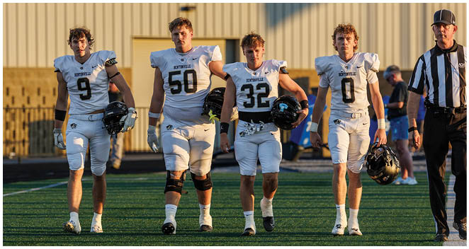 A group of football players walking on the field. Description generated by AI