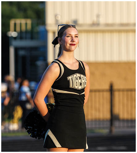 A cheerleader wearing a black and white uniform. Description generated by AI