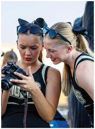 Two cheerleaders looking at a camera. Description generated by AI