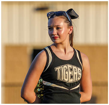 A cheerleader wearing a black and white uniform. Description generated by AI