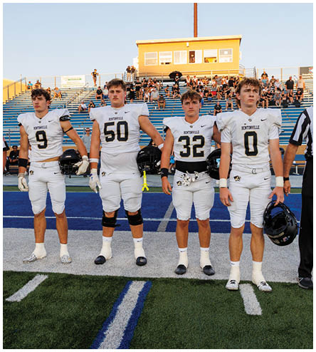 A group of football players standing on a field. Description generated by AI