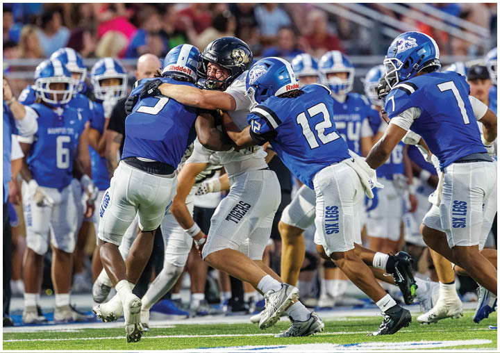 A group of football players in blue and white uniforms are playing a game. Description generated by AI