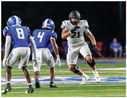 A football player in a white jersey running on the field. Description generated by AI