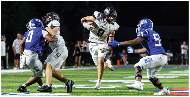 A football player in a white jersey is running with the ball. Description generated by AI