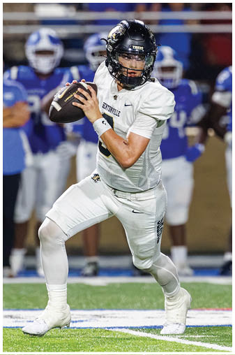 A football player in a white uniform holding a football. Description generated by AI