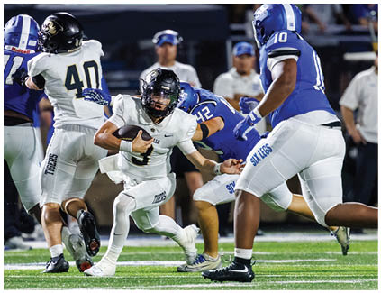 A football player in a white uniform is running with the ball. Description generated by AI