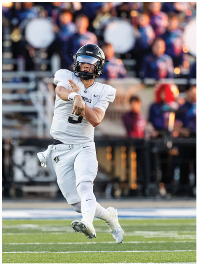 A football player in a white uniform throws a football. Description generated by AI