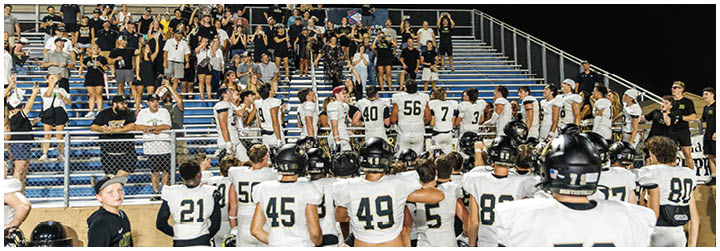 A group of football players standing on a field. Description generated by AI