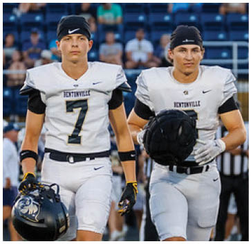 A group of football players standing on a field. Description generated by AI