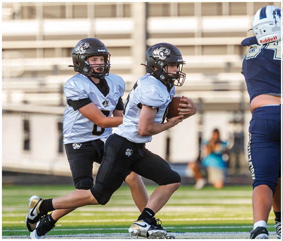 Three football players standing on a field. Description generated by AI