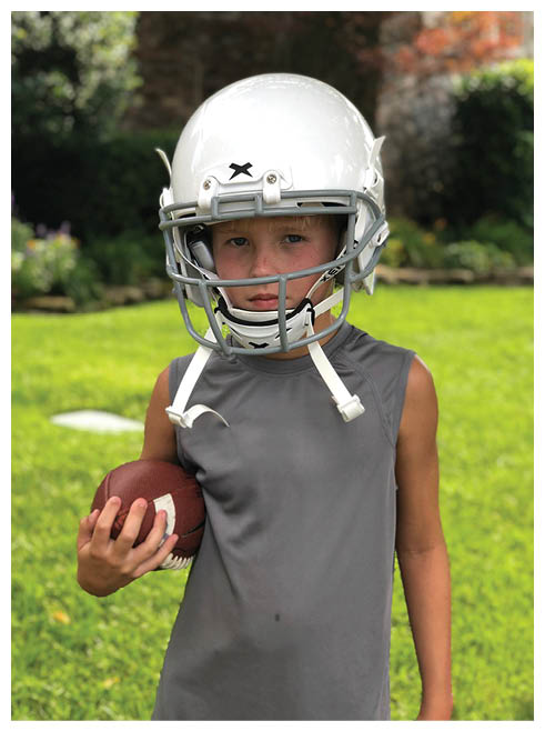 A young boy wearing a football helmet. Description generated by AI