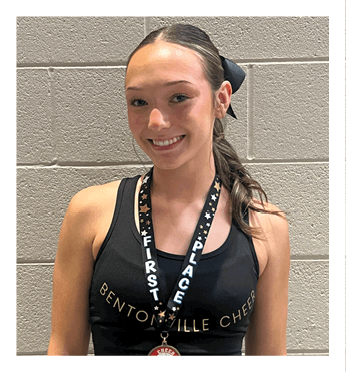 A woman wearing a black tank top with a gold medal around her neck. Description generated by AI