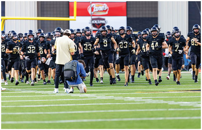 A group of football players standing on a field. Description generated by AI