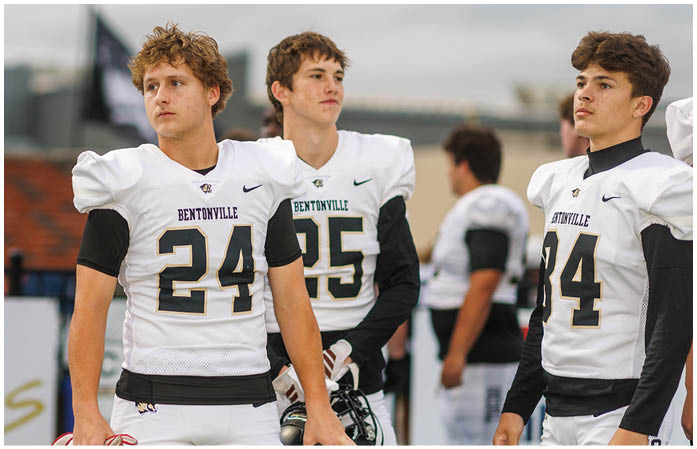 A group of football players standing on a field. Description generated by AI
