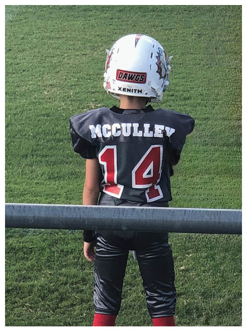 A young boy wearing a football jersey with the number 14. Description generated by AI