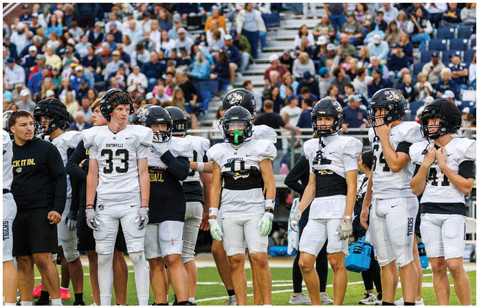 A group of football players standing on a field. Description generated by AI