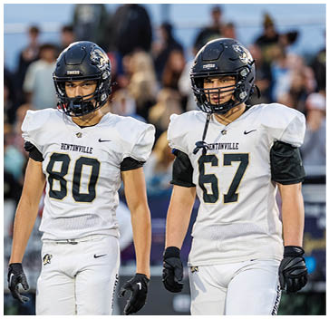 A group of football players standing on a field. Description generated by AI