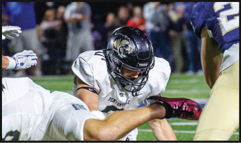 Two men wearing football uniforms are hugging each other on a field. AI generated content
