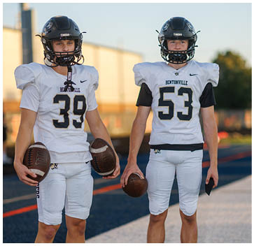A group of football players standing on a field. Description generated by AI