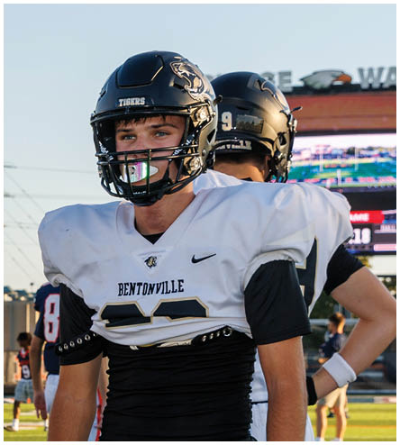 A football player wearing a black helmet and white jersey. Description generated by AI