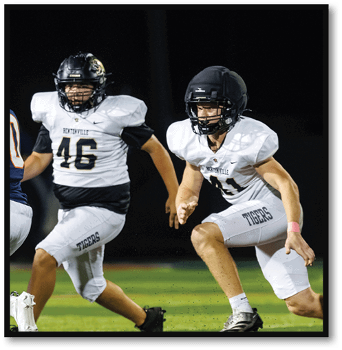 Two football players wearing black jerseys with the number 11 on them. Description generated by AI