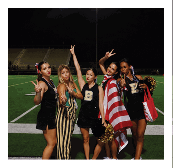 Four cheerleaders pose for a picture on a football field. Description generated by AI