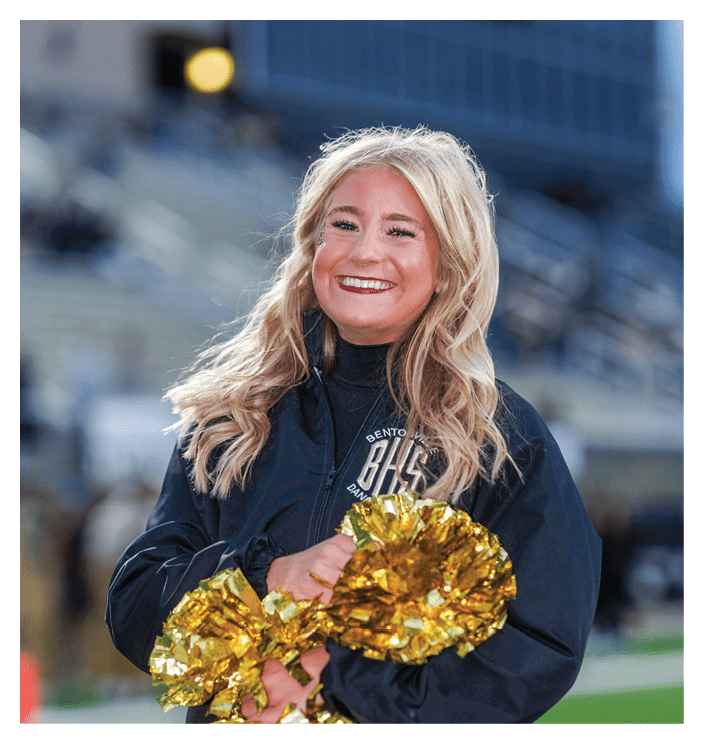 A football game is in progress with players on the field. One player is throwing a football while another player is trying to catch it. The players are wearing uniforms and are actively engaged in the game. AI generated content