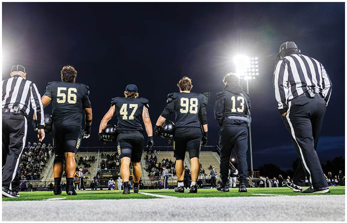 A group of football players standing on a field. Description generated by AI