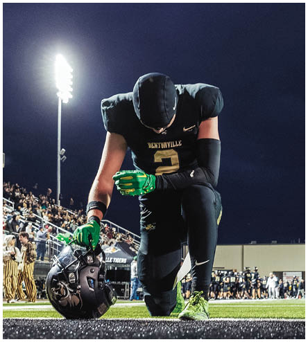 A football player wearing a black helmet and white jersey. Description generated by AI